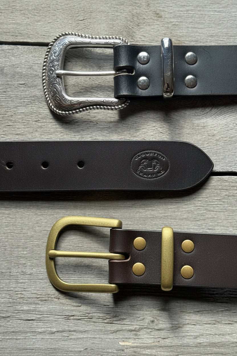 Two leather belts with metal buckles on a wooden surface
