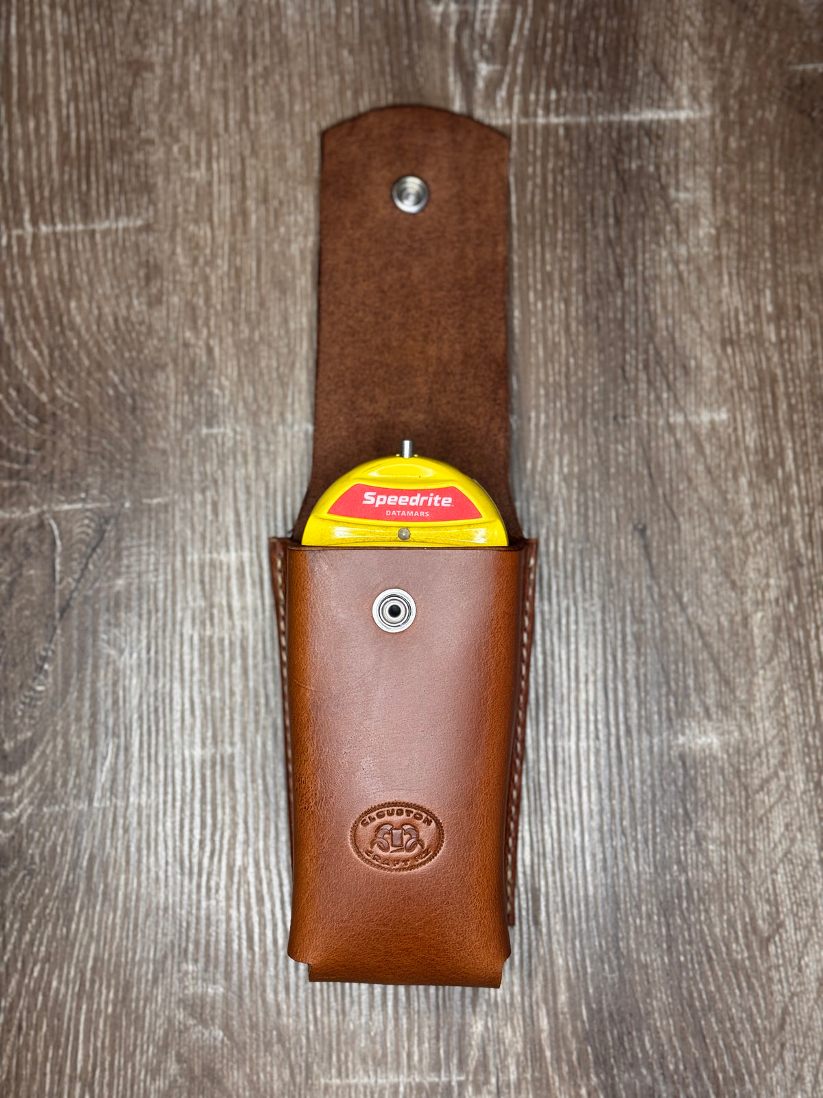 Brown leather tool pouch with Speedrite tool on a wooden surface