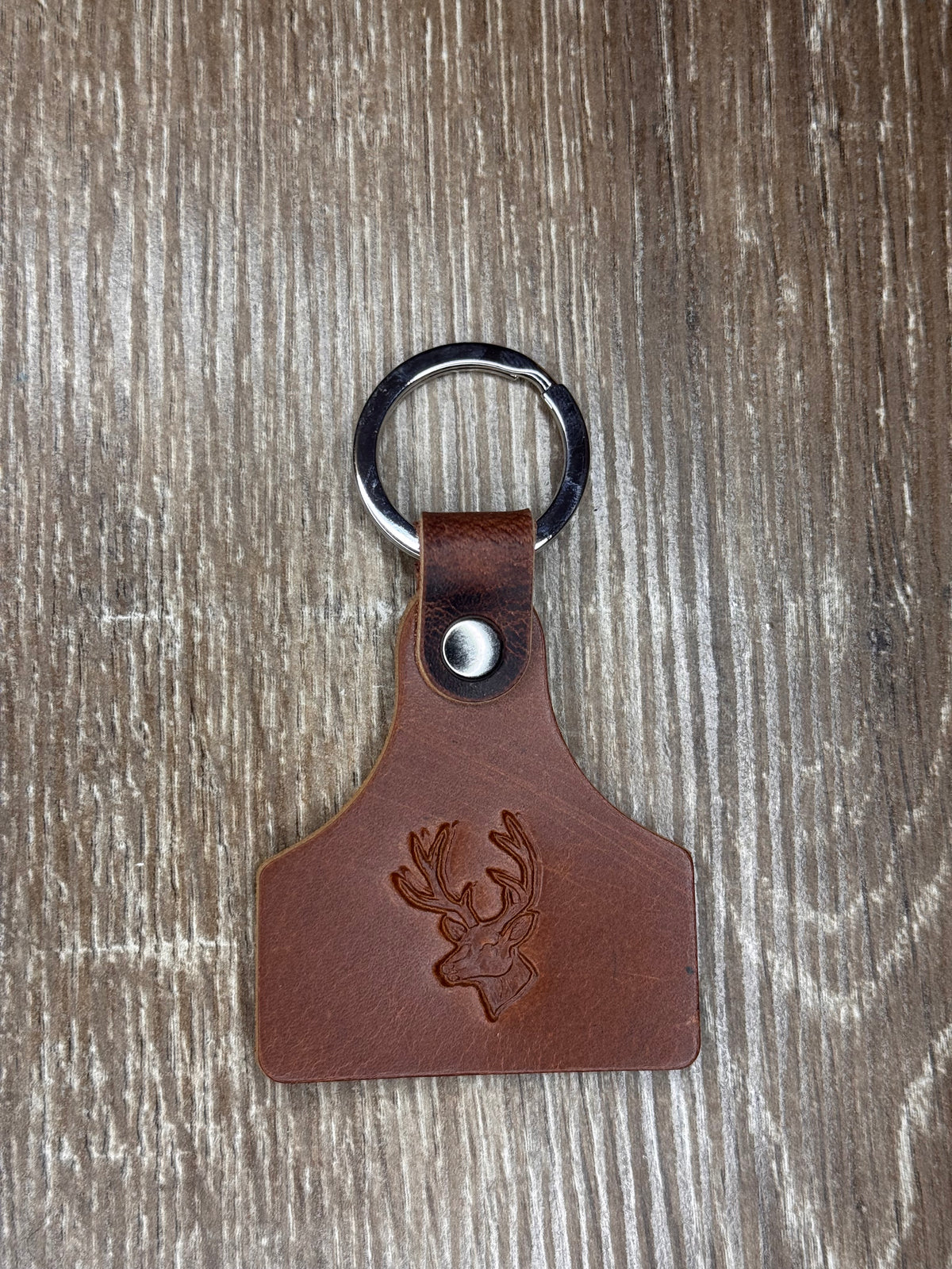 Brown leather keychain with metal ring on a wooden surface